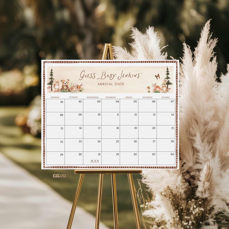 K&ouml;nnte beinhalten: Ein dekorativer Kalender auf einer goldenen Staffelei mit dem Text "GUESS BABY JENKINS ARRIVAL DATE" oben. Der Kalender hat ein Juli-Layout mit Daten und Illustrationen von Waldtieren. Der Hintergrund ist verschwommen mit neutralen T&ouml;nen.