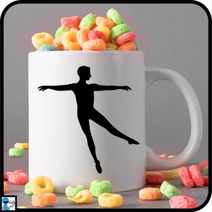 May include: White ceramic mug with a black silhouette of a dancer in a ballet pose. The mug is filled with colorful cereal.
