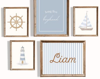 May include: Five framed nautical-themed prints. The prints include a ship's wheel, a sailboat, a lighthouse, a blue background with the text "long live boyhood", and a blue striped print with the name "Liam".