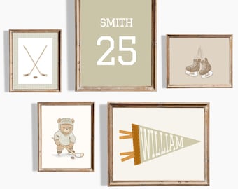 May include: A set of five framed prints with a hockey theme. The prints feature a hockey stick and puck, a bear wearing a hockey jersey, a pennant with the name "William", a pair of hockey skates, and a name and number, "Smith 25".