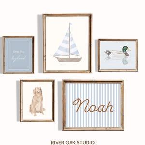 May include: A collection of five framed art prints with a nautical theme. The prints feature a sailboat, a duck, a golden retriever, a blue striped background with the name "Noah", and a print with the text "long live boyhood".