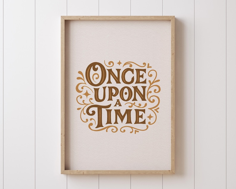 May include: A framed print with the words "ONCE UPON A TIME" in a decorative, vintage-style font. The text is in a warm brown color and is surrounded by ornate flourishes. The frame is a light wood color, and the background is a neutral off-white.