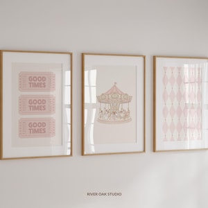 May include: Three framed art prints with a light wood frame. The left print has three pink tickets that say "GOOD TIMES". The middle print has a carousel illustration. The right print has a pink diamond pattern.