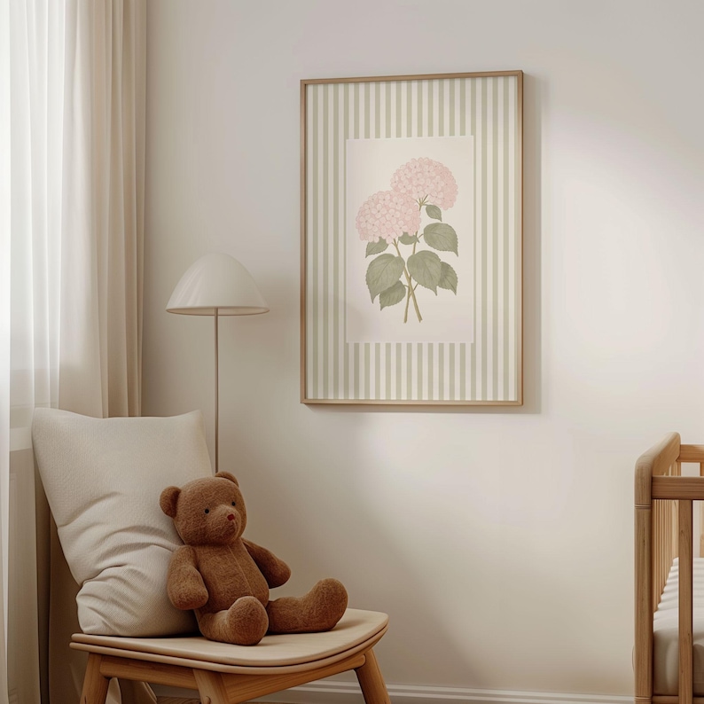 K&ouml;nnte beinhalten: Gerahmter Kunstdruck mit rosa Hortensienbl&uuml;ten und gr&uuml;nen Bl&auml;ttern. Das Kunstwerk ist vor einem gestreiften Hintergrund in einem hellen Beige- und Wei&szlig;ton gehalten. Ein brauner Teddyb&auml;r sitzt auf einem Holzstuhl.