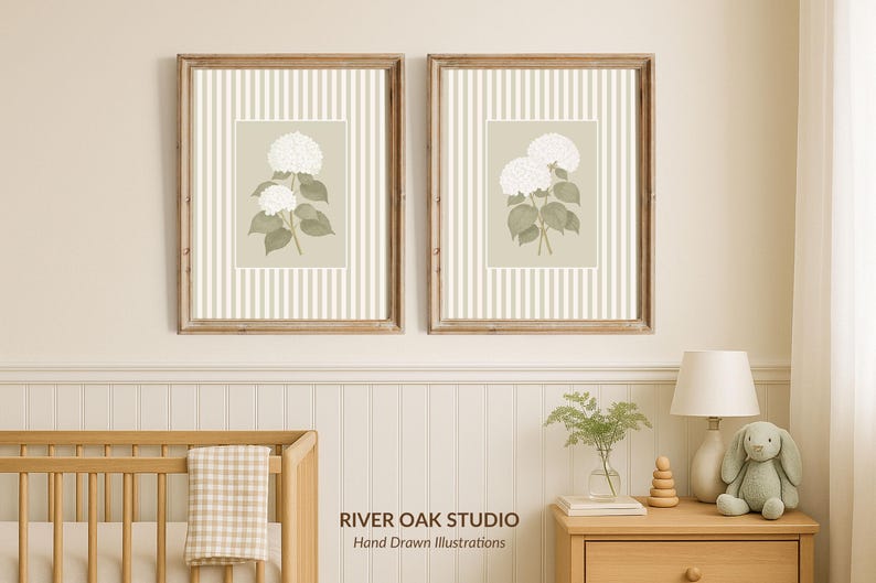May include: Two framed botanical prints featuring white hydrangea flowers with green leaves. The artwork is set against a striped background in a neutral color palette. The frames are made of wood. The prints are displayed above a crib.