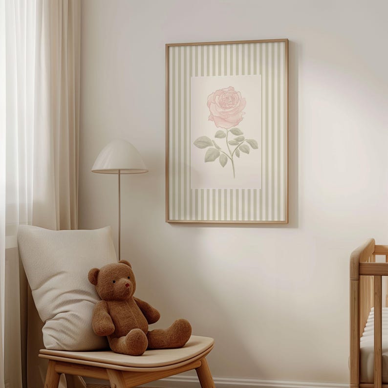 May include: A framed botanical print featuring a pink rose with green leaves and stem. The artwork is set against a striped background in a wooden frame. A teddy bear sits on a wooden chair next to the artwork.