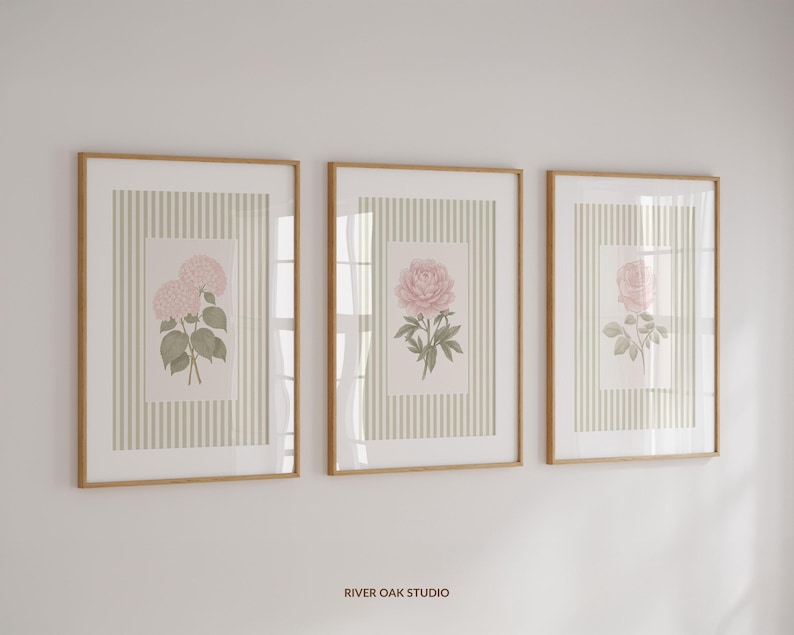 K&ouml;nnte beinhalten: Drei gerahmte botanische Drucke mit floralen Illustrationen. Jeder Druck hat einen hellbraunen Holzrahmen und einen cremefarbenen Hintergrund mit vertikalem Streifenmuster. Die floralen Illustrationen zeigen rosa Hortensien, Pfingstrosen und Rosen.