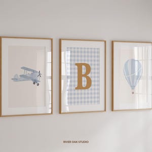 May include: Three framed prints featuring a blue and white gingham pattern, a blue aeroplane, and a blue hot air balloon. The centre print displays the letter "B" in gold.