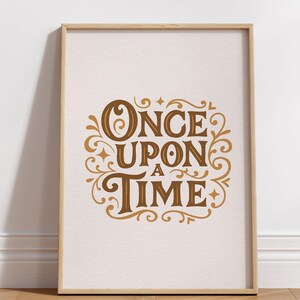 May include: A framed print with the words "ONCE UPON A TIME" in a decorative, vintage-style font. The text is in shades of brown and gold against a cream-colored background. The frame is a light wood color.