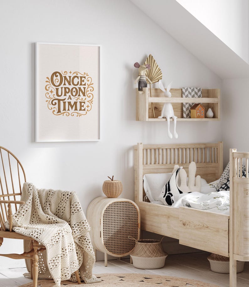 May include: A framed print with the words "Once Upon a Time" in gold script hangs on a white wall. The room features a wooden bed, a woven chair, and a woven side table. A cream-colored blanket is draped over the chair.