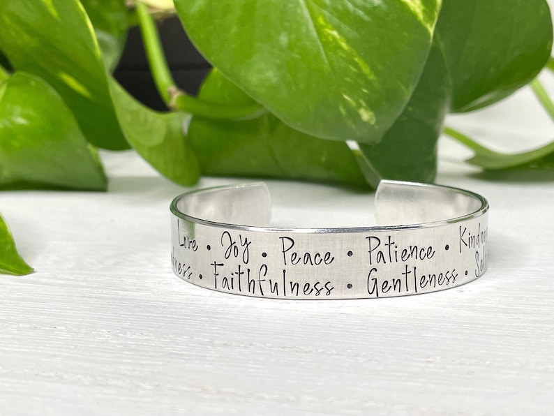 May include: Silver metal bracelet engraved with the words "Love, Joy, Peace, Patience, Kindness, Faithfulness, Gentleness, Self-Control".