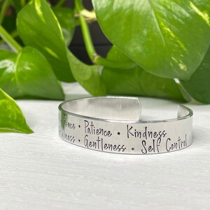 May include: Silver bracelet engraved with the words "Peace, Patience, Kindness, Gentleness, Self Control".