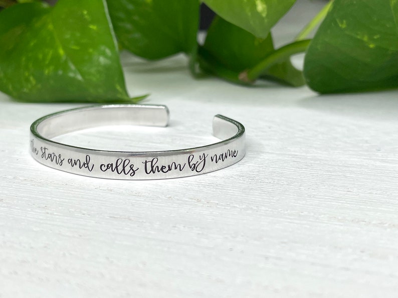 May include: Silver bracelet with the inscription "He knows the stars and calls them by name".