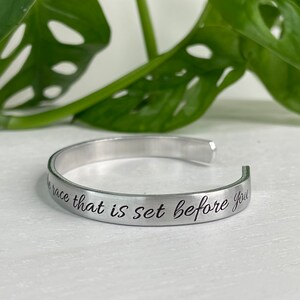 May include: Silver bangle bracelet with the inscription "Run the race that is set before you".