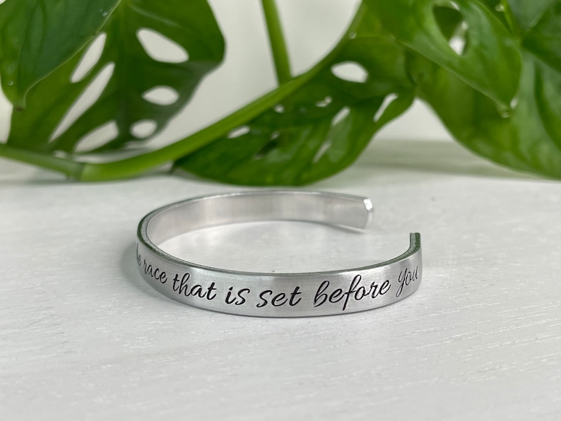 May include: Silver bangle bracelet with the inscription "Run the race that is set before you".