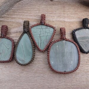 May include: Five pendants with different shaped stones, each wrapped in brown or black cord. The stones are green and have a marbled pattern.