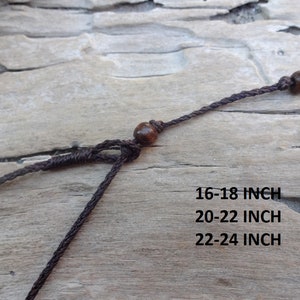 May include: Brown cord necklace with wooden beads. The necklace is available in three lengths: 16-18 inch, 20-22 inch, and 22-24 inch.