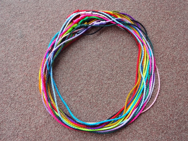 May include: A circle of colorful embroidery floss, arranged in a circular pattern, with a variety of colors including pink, blue, green, yellow, and orange.