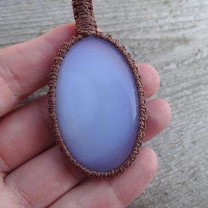 Peut inclure: Pendentif en pierre pr&eacute;cieuse ovale bleu clair, serti dans un tissage macram&eacute; marron. Le pendentif a une surface lisse et polie et un aspect translucide. Le cordon macram&eacute; est finement tiss&eacute; autour de la pierre.