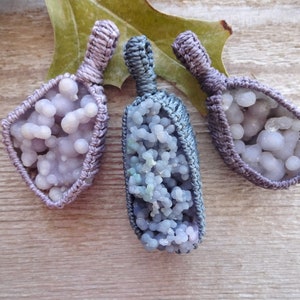 May include: Three purple and blue agate pendants with a knotted cord loop. The agate is a druzy variety with a cluster of small crystals.