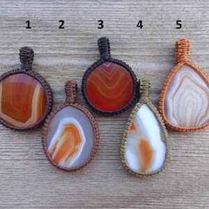 May include: Five agate stone pendants with macrame cord, numbered 1 through 5. The stones are various shades of brown, orange, and white.