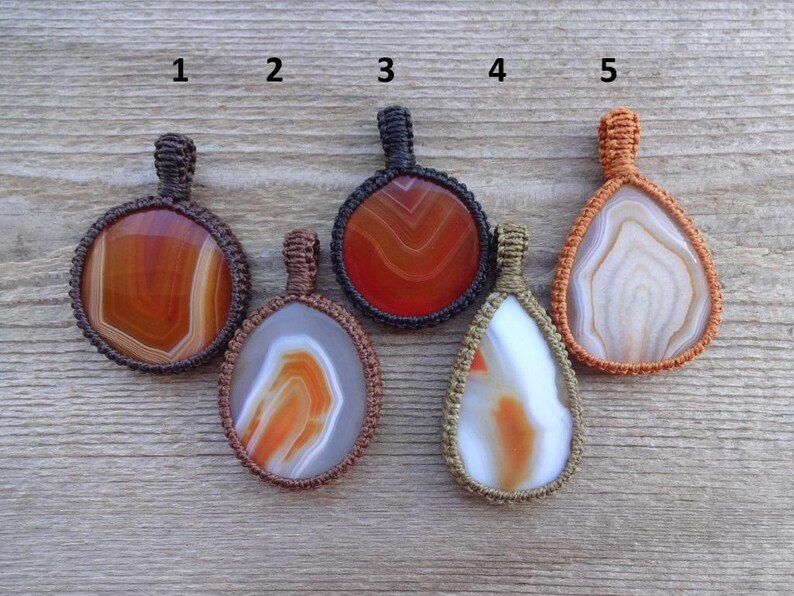 May include: Five agate stone pendants with macrame cord, numbered 1 through 5. The stones are various shades of brown, orange, and white.