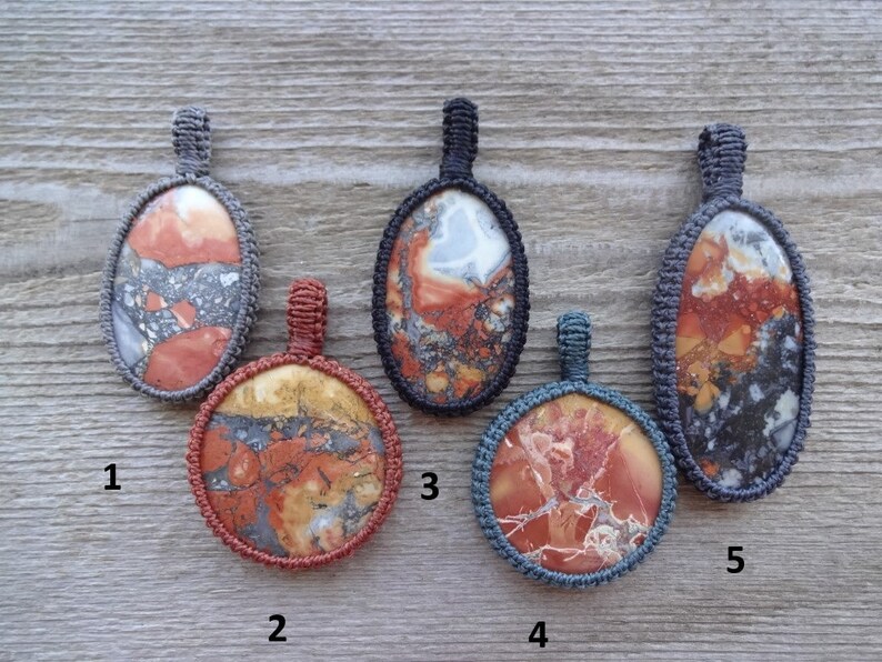 May include: Five oval-shaped pendants with different patterns of red, orange, brown, white, and black. Each pendant is surrounded by a gray or blue cord.