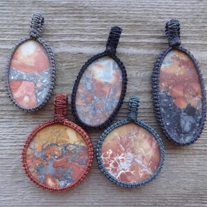 May include: Five pendants with different patterns of red, orange, and gray stone set in gray, blue, and red cord.