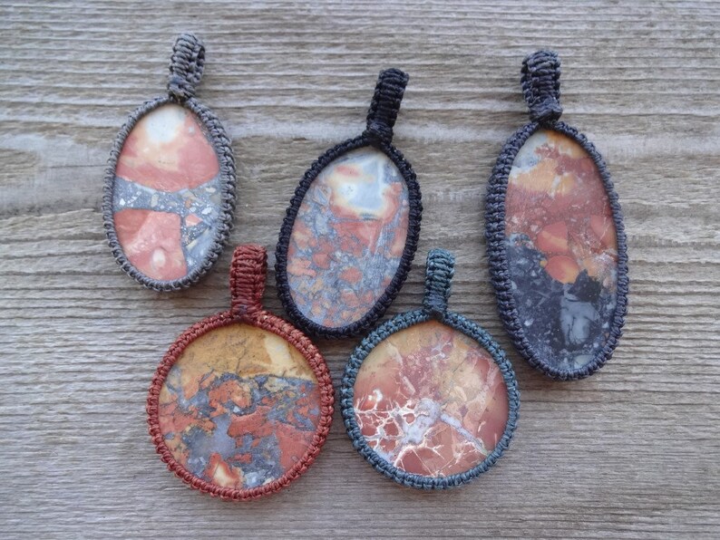 May include: Five pendants with different patterns of red, orange, and gray stone set in gray, blue, and red cord.