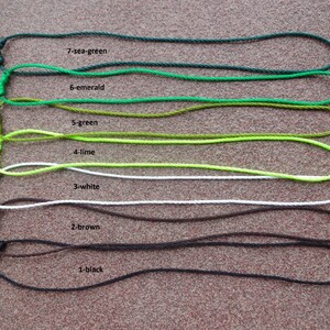 May include: Seven different colors of cord, each tied in a loop. The colors are sea green, emerald green, green, lime green, white, brown, and black. The cords are labeled with their color and number.