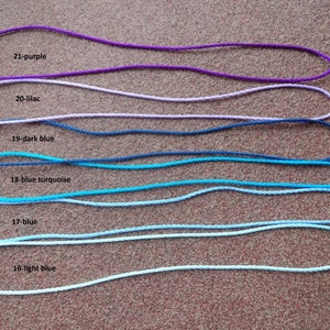 May include: Six different colors of cord, from light blue to purple, are laid out in a row. Each cord has a knot at one end and is labeled with a number and color. The colors are light blue, blue, blue turquoise, dark blue, lilac, and purple.