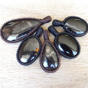 May include: Five black gemstone pendants with brown cord wrappings. The gemstones are oval and teardrop shaped.