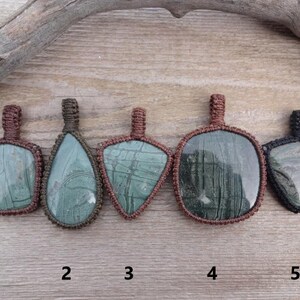 May include: Five green and brown stone pendants with different shapes and patterns, each with a brown cord loop at the top. The pendants are numbered 1 through 5.