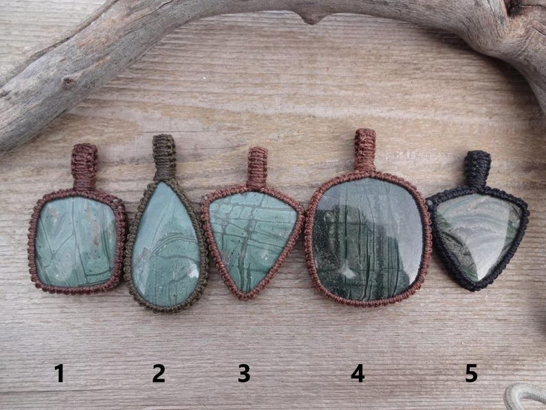 May include: Five green and brown stone pendants with different shapes and patterns, each with a brown cord loop at the top. The pendants are numbered 1 through 5.