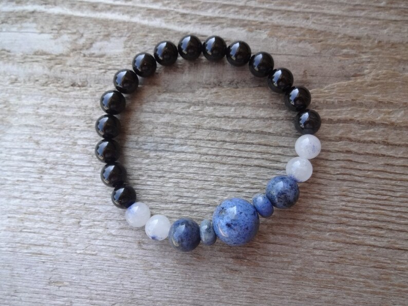 Op de afbeelding: Een armband van zwarte onyx en blauwe lapis lazuli kralen met een grotere lapis lazuli kraal in het midden.