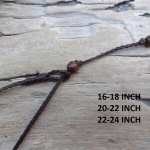 May include: Close-up of a brown necklace with wooden beads and adjustable cord. The text on the image indicates the necklace is available in 16-18 inch, 20-22 inch, and 22-24 inch lengths.