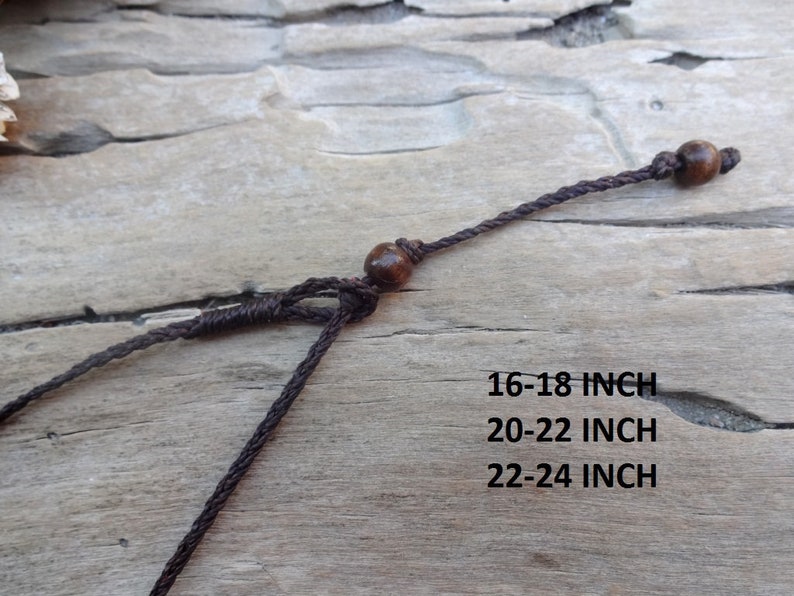 May include: Close-up of a brown necklace with wooden beads and adjustable cord. The text on the image indicates the necklace is available in 16-18 inch, 20-22 inch, and 22-24 inch lengths.