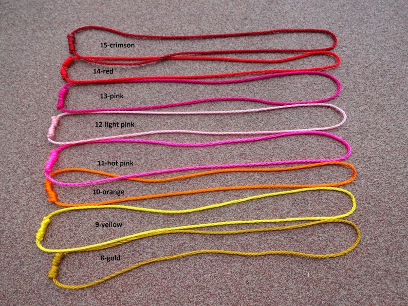 May include: Eight cords of different colors, from gold to crimson, are laid out in a row on a textured surface. Each cord is labeled with a number and color name, such as "8-gold" and "15-crimson".
