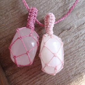 May include: Two pink rose quartz stones are wrapped in pink macrame cord and strung on a pink cord necklace.