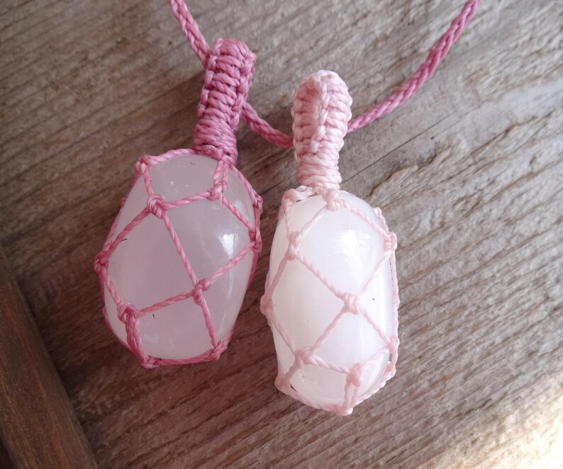 May include: Two pink rose quartz stones are wrapped in pink macrame cord and strung on a pink cord necklace.