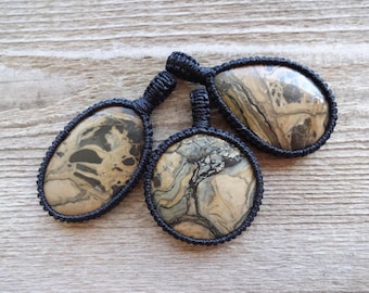 May include: Three oval-shaped pendants with a black cord and a brown and black marbled stone.