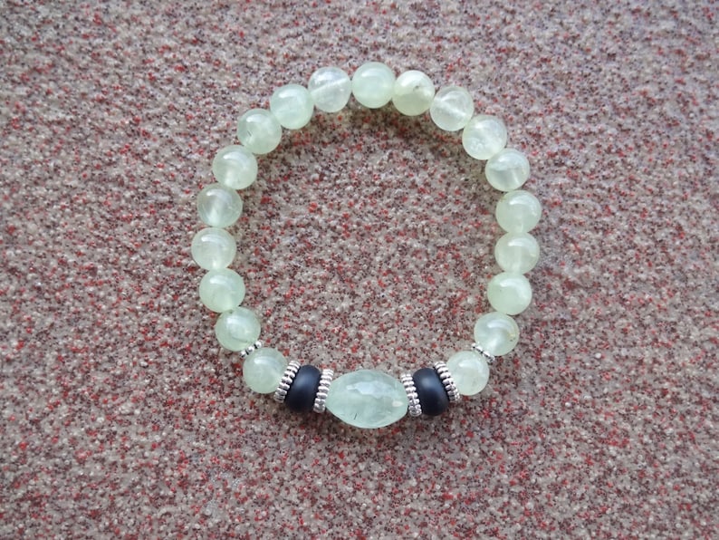 May include: A green gemstone bracelet with silver accents and a larger green gemstone in the center.