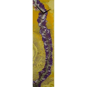 Puede incluir: Un reloj rectangular alto con un diseño abstracto amarillo y morado. La esfera del reloj es negra con manecillas blancas.