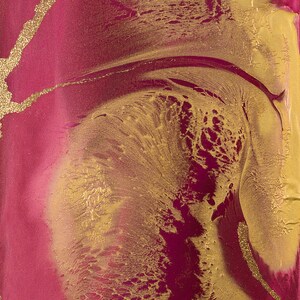 Puede incluir: Una esfera de reloj dorada con agujas doradas sobre un fondo de marmoleado abstracto rosa y dorado.