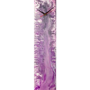 May include: A long, vertical clock with a purple, white and silver abstract design. The clock face is white with black hands.