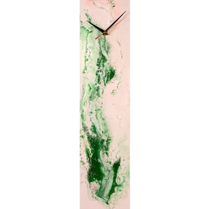 Pode incluir: Um relógio vertical longo com um design abstrato rosa e verde. O mostrador do relógio é branco com ponteiros pretos.