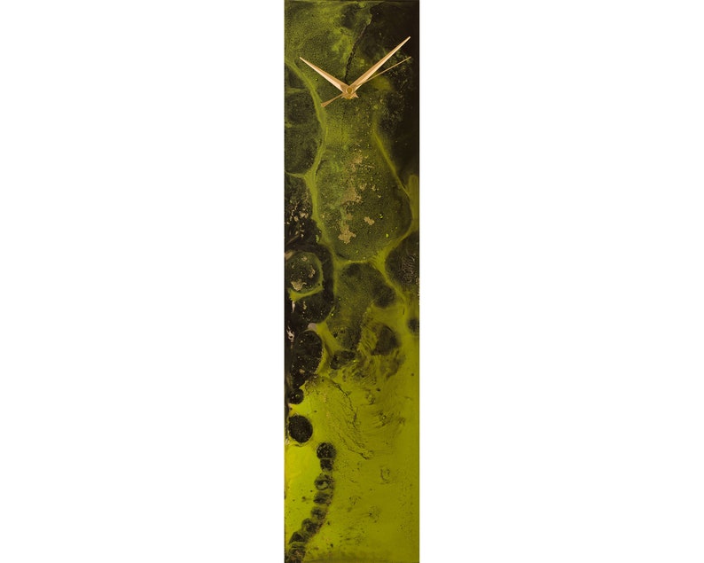 Op de afbeelding: Een verticale klok met een abstract ontwerp in zwart en groen. De wijzerplaat van de klok is wit met gouden wijzers.