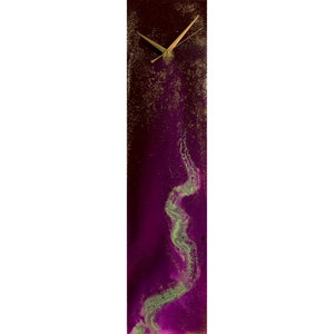 Puede incluir: Un reloj rectangular alto con fondo morado y detalles dorados. La esfera del reloj es blanca con agujas negras. El fondo presenta un dise&ntilde;o verde y dorado en espiral.