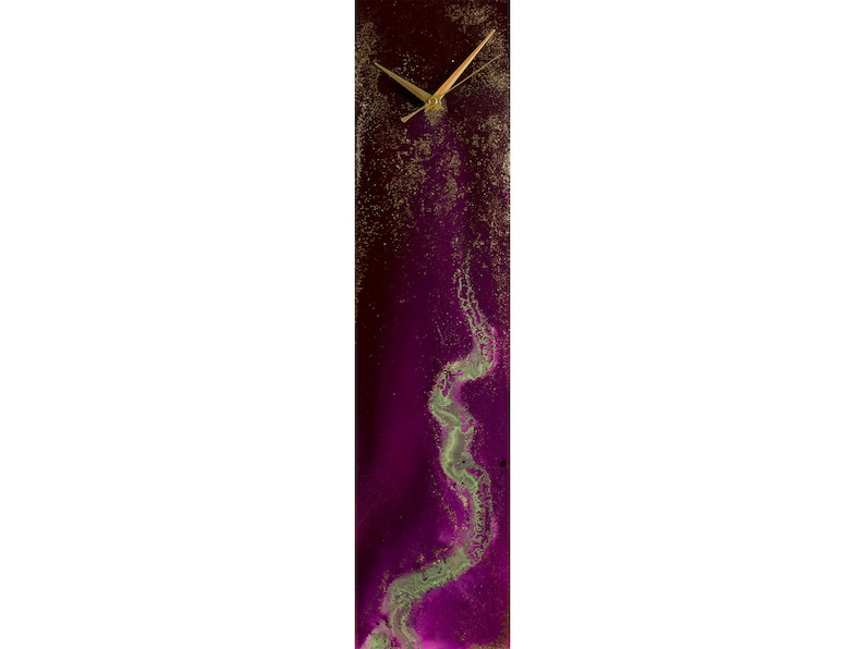 Puede incluir: Un reloj rectangular alto con fondo morado y detalles dorados. La esfera del reloj es blanca con agujas negras. El fondo presenta un dise&ntilde;o verde y dorado en espiral.