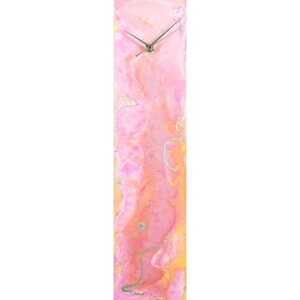 May include: A long, rectangular clock with a pink and orange abstract design. The clock face is white with silver hands.